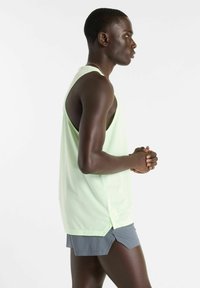Light green sleeveless performance tank top, mesh texture, side vents, paired with gray athletic shorts. Simple, functional design.