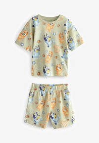Children's pajamas in light green, featuring cartoon dogs in blue, orange, and yellow. Loose fit with a short-sleeve top and elastic waistband shorts.