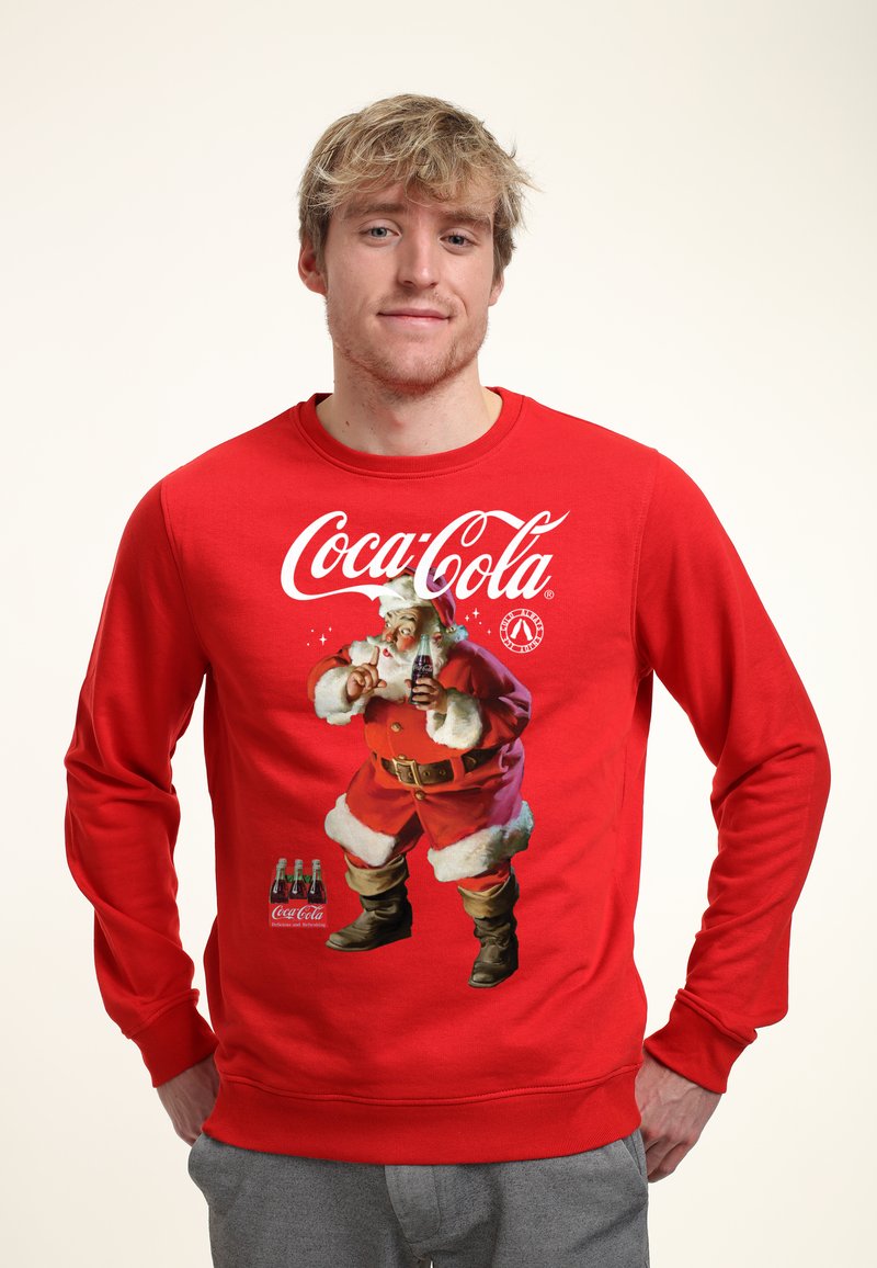 Červená mikina s logem Coca-Cola a grafikou Santa Clause. Měkká tkanina s dlouhými rukávy a žebrovanými manžetami.