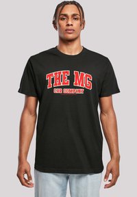 Black cotton T-shirt featuring bold red text "THE MG CAR COMPANY" across the chest, crew neck, and short sleeves. Simple, casual design.