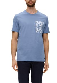 Hellblaues Baumwoll-T-Shirt mit einer weißen, blattmusterförmigen Tasche auf der linken Brust. Kurze Ärmel und runder Ausschnitt.
