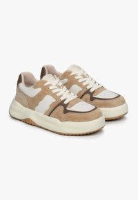 Beige en witte sneakers van suede en leer. Kenmerken zijn onder andere een ronde vorm, vetersluiting en een gestructureerde rubberen zool met accenten.