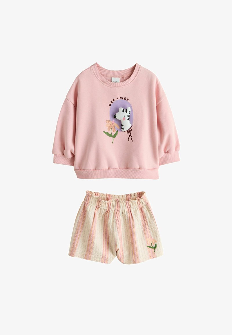 Sweat-shirt rose à manches longues avec inscription « Dreamer » et motif zèbre, associé à un short beige rayé à taille élastique avec une petite broderie fleurie.