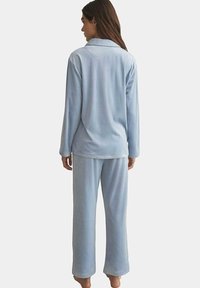 Ensemble de pyjama bleu clair en polaire douce, comprenant une chemise à manches longues avec boutons et un pantalon ample, doté d'un col classique et de coutures soignées.