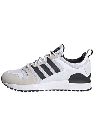 Białe i szare buty sportowe Adidas z czarnymi paskami, wiązane, z teksturowaną podeszwą, widoczne z boku na białym tle.
