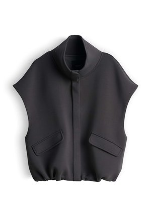 Gilet nero senza maniche con colletto alto, patta frontale, due tasche con patta e orlo arricciato su sfondo bianco.