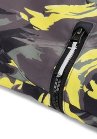 Stof met camouflagepatroon in tinten grijs, geel en groen. Voorzien van een zwarte rits met een witte accenten en een gestructureerd oppervlak.