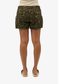 Pantalones cortos cargo de camuflaje verde con cintura elástica y bolsillos traseros, que muestran un ajuste relajado y una textura de algodón cepillado.