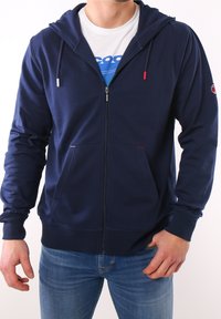 Granatowy rozpinany polar z mieszanki bawełny, z przednim zamkiem, dwiema kieszeniami, kapturem na sznurku oraz logo na rękawie.