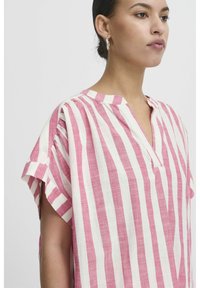 Blusa in lino a righe rosa e bianche con scollatura a V, maniche corte e una vestibilità rilassata. Tessuto con texture visibile.