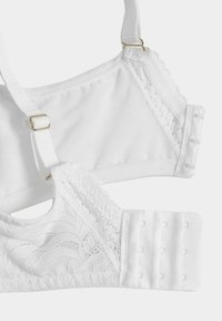 Reggiseno bianco con bordi in pizzo, spalline regolabili e chiusura a gancio. Tessuto liscio con una sezione testurizzata a contrasto.