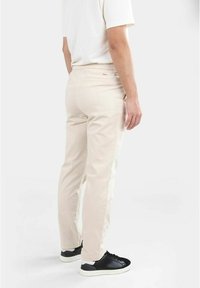 Beige bomullschinos med resårmidja. Har en bakficka och en subtil logodetalj. Matcher med svarta sneakers.