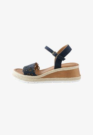 Marineblaue Keilsandalette mit Knöchelriemen, florales Cut-out-Design am Zehenriemen, geflochtene Juteverzierung und weißer Gummisohle.