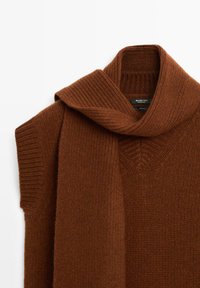Pull sans manches marron en tricot avec une longue écharpe assortie drapée autour du col, en 100 % laine.