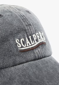 Gorra de tejido gris con un logo bordado de "SCALPERS" en blanco, con una sutil línea de acento marrón debajo del texto.