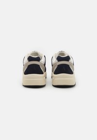 Due sneaker rivolte all'indietro, con tomaia in suede e mesh blu navy, dettagli crema e una suola intermedia beige con una parte inferiore nera testurizzata.