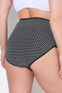 Bikini bottom a vita alta in nero con pois bianchi. Presenta un tessuto liscio, una forma arrotondata e un bordo nero solido lungo i lati.