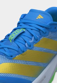 Chaussure de course Adidas Adizero bleue et jaune avec des lacets bleus et une tige en mesh, dotée de bandes jaunes et du logo sur la languette.