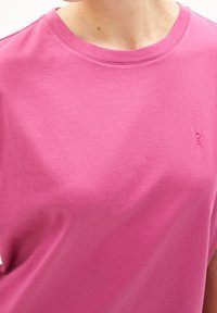 T-shirt in cotone rosa con scollo rotondo e maniche corte. Presenta un logo ricamato discreto nell'angolo in basso. Texture morbida.