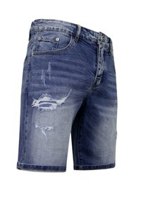 Denim shorts in een vervaagde blauwe wassing, met gescheurde patches en een licht uitrafelde zoom. Voorzien van standaardzakken en metalen hardware.