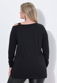 Schwarzes Langarmtop mit einem schulterfreien Design. Hergestellt aus weichem Stoff, mit einer lockeren Passform und einem abgerundeten Saum auf Höhe der Taille.