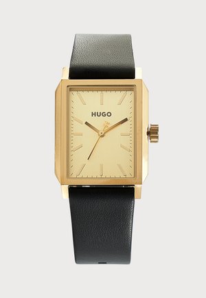 Montre-bracelet rectangulaire Hugo en or avec bracelet en cuir noir et index simples dorés sur un cadran or clair.