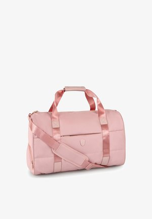Sac de sport cylindrique rose clair avec poignées en satin, bandoulière réglable, poche zippée à l'avant, et petit emblème logo.