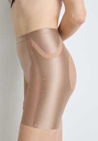 Pantalones cortos ajustados de color marrón claro, hechos de una tela suave con un diseño elegante. Presentan costuras cosidas y un panel semi-translúcido en el costado.
