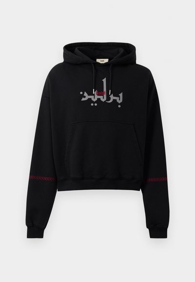 Felpa corta nera con cappuccio e cordino, con testo arabo in accenti argento e rosso sui polsini. Tessuto morbido, design con tasca a marsupio.