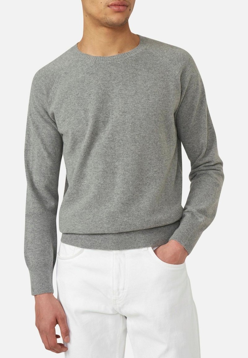 Hellgrauer Strickpullover mit Rundhalsausschnitt, langen Ärmeln und geripptem Saum. Kombiniert mit weißen Hosen, die eine glatte Stofftextur zeigen.