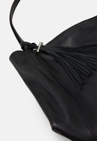 Czarna skórzana torebka o teksturowym wykończeniu, z długim przypinką w kształcie frędzla oraz eleganckim, trójkątnym kształtem. Zawiera pasek na ramię.