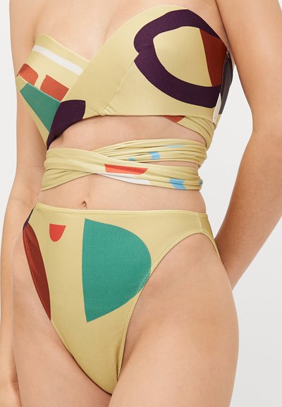 Kollane bikinikomplekt, millel on abstraktsed kujundid rohelise, pruuni, punase ja sinisega. Väljalõigatud bandeau-topp ja kõrge vöökoht.