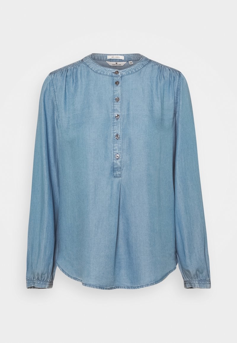 Blouse en denim bleu clair à manches longues, col rond et cinq boutons sur la patte de boutonnage avant, avec de légers fronces aux épaules et aux poignets.