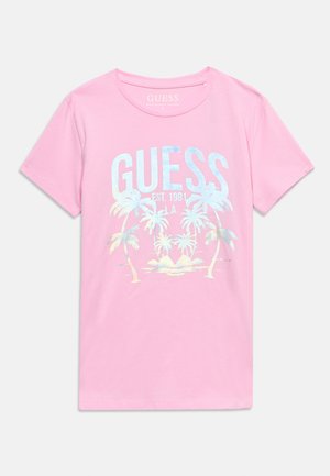 Ružičasta majica kratkih rukava s tekstom "GUESS EST. 1981 L.A." i grafikom palme u svijetlim pastelnim bojama na prednjoj strani.