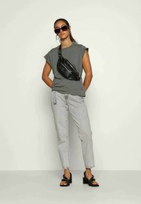 Gray short-sleeve top, high-waisted light denim jeans, black crossbody bag, and black strappy sandals with a block heel. Large sunglasses worn.