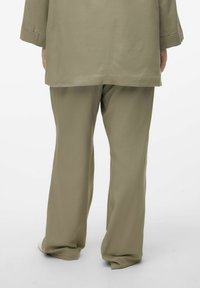 Khaki to-delt outfit med en løs skjorte og bredbenede bukser, lavet af et glat, let materiale.