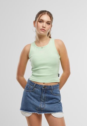 Light green ribbed crop top with a crew neck and logo detail, paired with a high-waisted denim mini skirt with frayed hem.