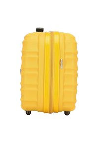 Valigia rigida gialla con texture a righe, zip liscia, ruote nere e maniglia laterale per un facile trasporto.