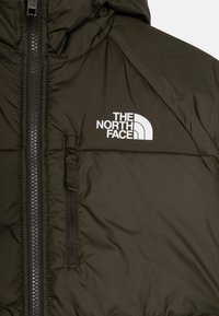 Ciemnozielona kurtka ocieplana z teksturowanej tkaniny, z przednim zamkiem błyskawicznym i boczną kieszenią z małą pętelką. Widoczne jest logo The North Face.