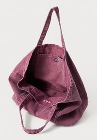 Purple canvas tote bag with sturdy handles, open top, and a small interior pocket. Soft texture with a faded appearance.