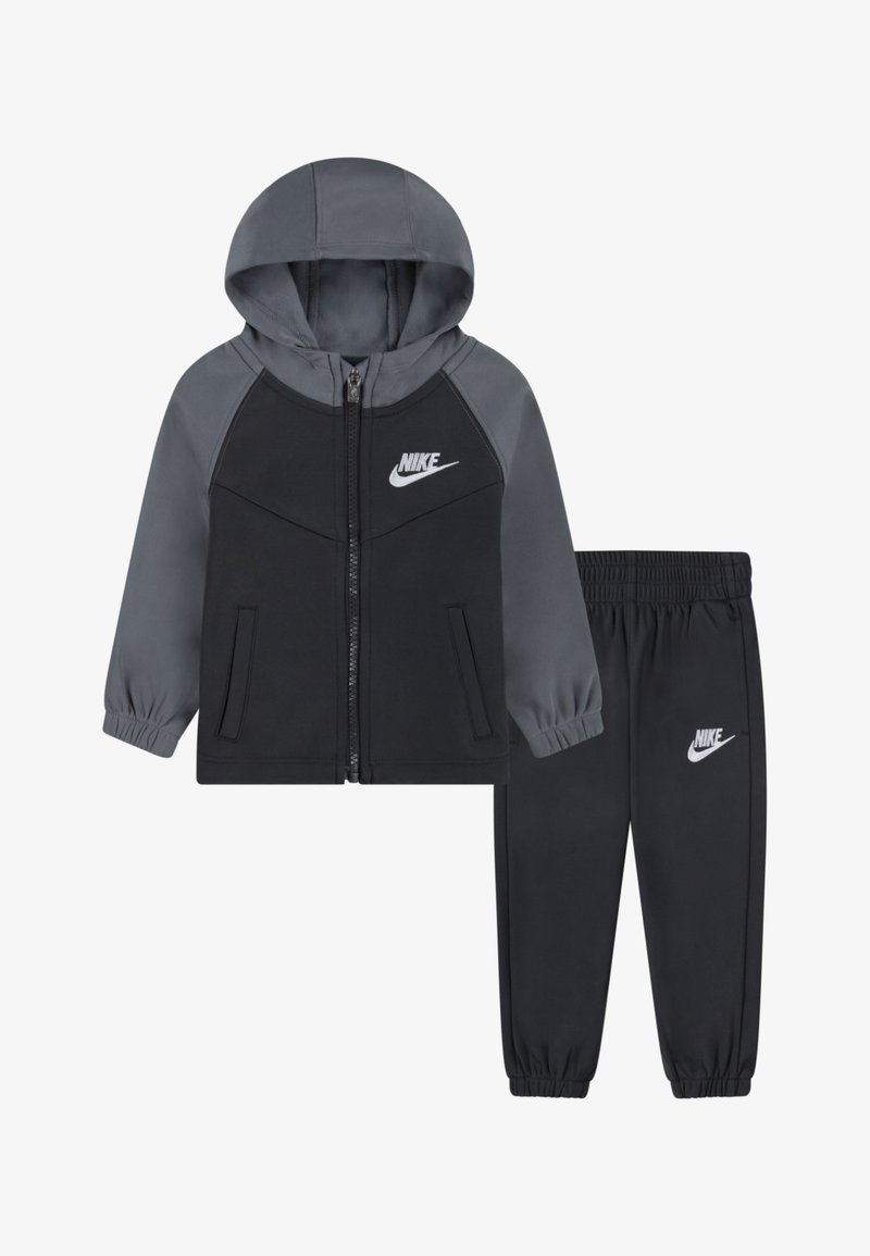 Fato de treino Nike em preto e cinza, com um hoodie com fecho e calças elásticas. Apresenta tecido macio, punhos elásticos e o logótipo emblemático em ambas as peças.