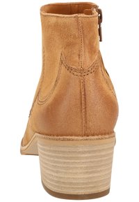 Tanový semišový kotníkový bot s kulatou špičkou, bočním zipem a nízkým širokým podpatkem. Podrobné prošívání a strukturovaný povrch vylepšují design.