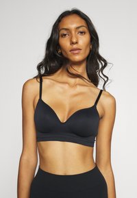 Black wireless bra with padded cups and a slight V-neck, features thin adjustable straps and a smooth fabric texture.