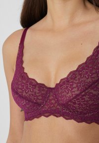 Lace bra in deep mauve, featuring scalloped edges, floral patterns, adjustable straps, and a sheer texture.
