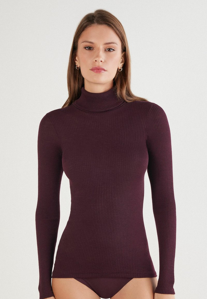 Burgunderfarbener, gerippter Rollkragenpullover, langärmlig, figurbetontes Design. Hergestellt aus weichem Material, mit subtiler Textur und minimalistischem Look.