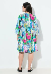 Vestido de estampado floral con colores vibrantes, mangas cortas de campana, cintura ajustada y falda de capas. Fabricado con una tela suave y con un ajuste relajado.