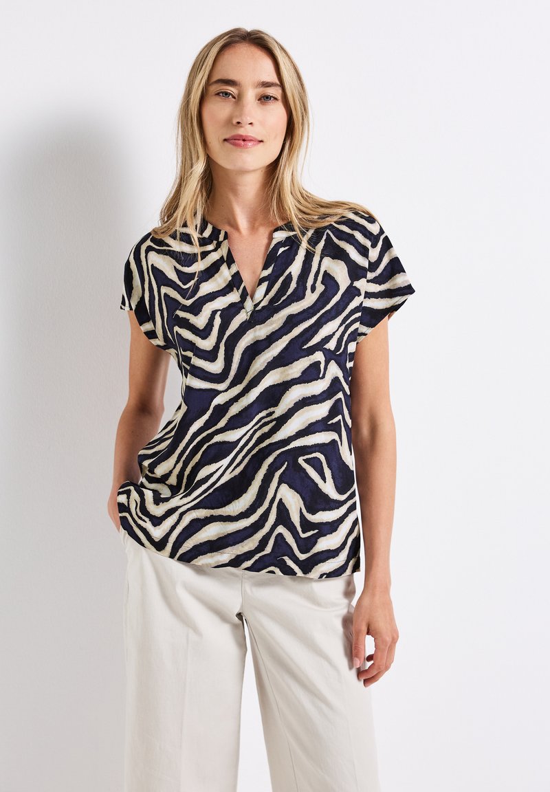 Short-sleeve blouse in navy and cream with an abstract zebra stripe pattern, featuring a v-neck and a loose-fitting design.