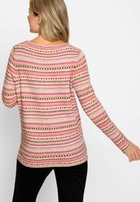Gebreide trui met een verscheidenheid aan roze, rode en bruine geometrische patronen op een crèmekleurige achtergrond. Lange mouwen en een ronde halslijn.