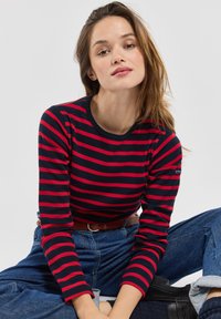 Rood en marineblauwe gestreepte lange mouwen top met een ronde hals en een getailleerde pasvorm. Textuurstof, met een klein logo op de mouw.