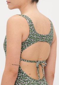 Maillot une-pièce vert à motifs avec un dos nageur, doté d'une fermeture par nouage et de motifs élaborés de cactus et de fleurs.